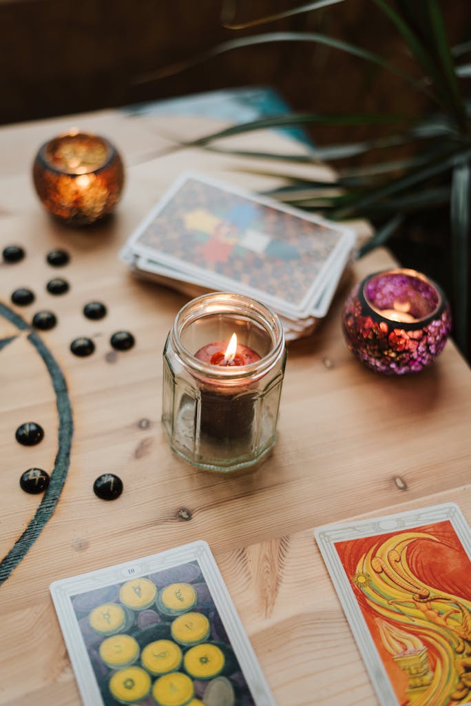 Burning candles near tarot cards on table