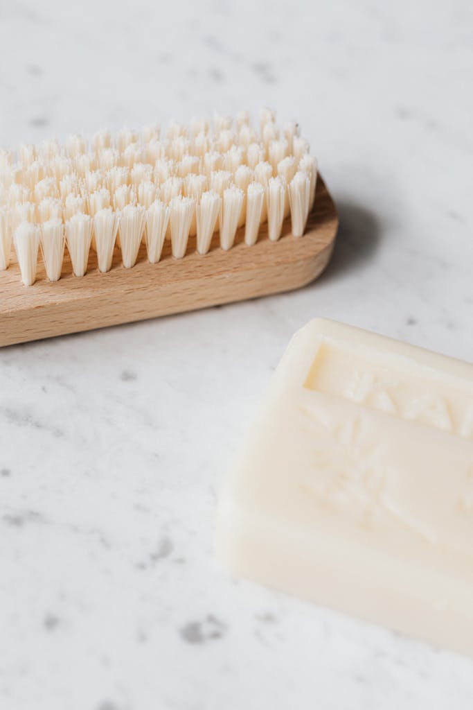 From above closeup of wooden cleaning brush and soap placed on marble table