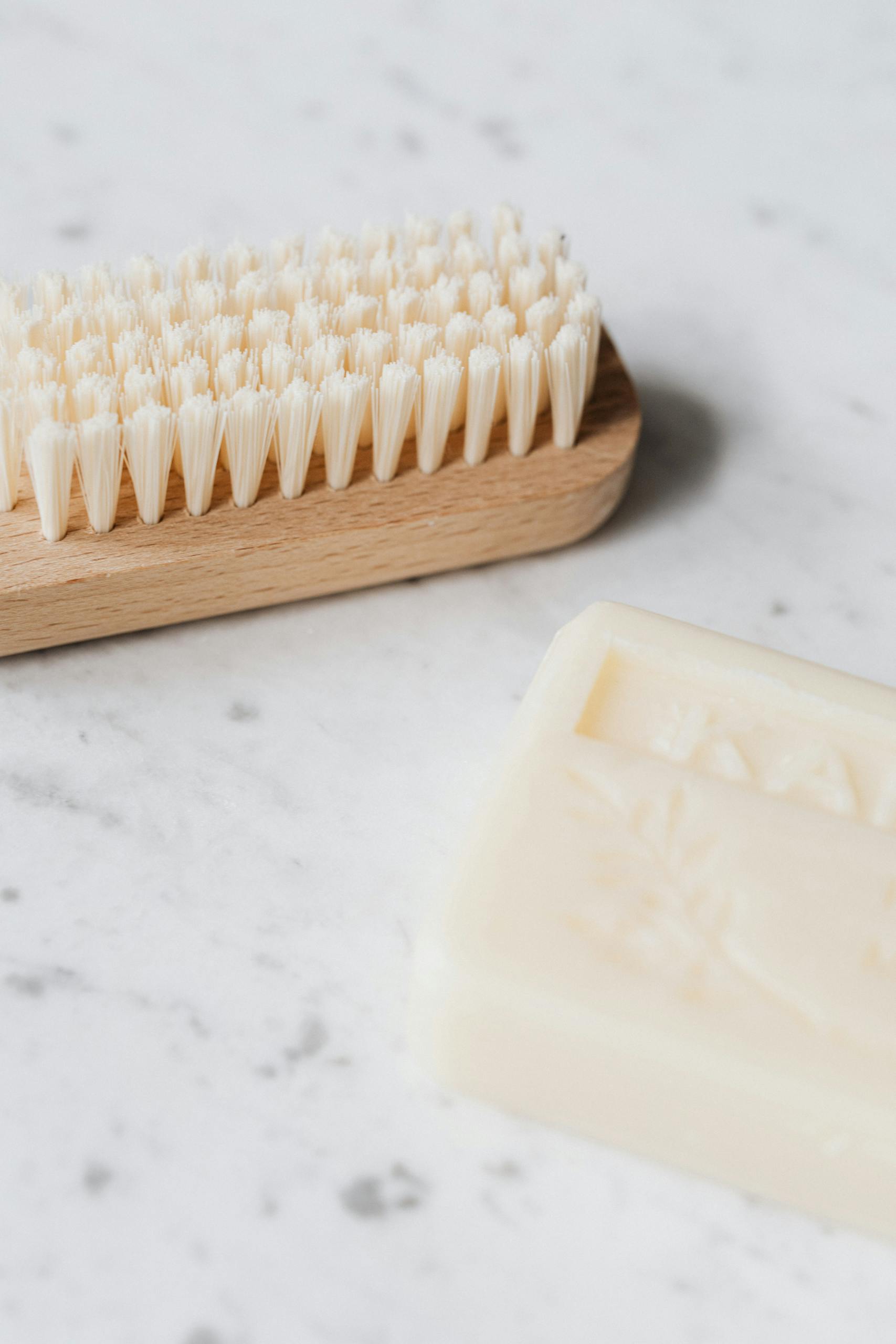 From above closeup of wooden cleaning brush and soap placed on marble table