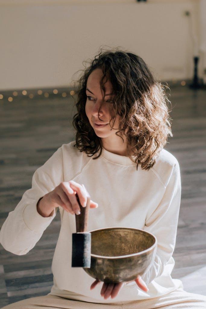 Woman in White Long Sleeve Shirt Holding a Tibetan Singing Bowl